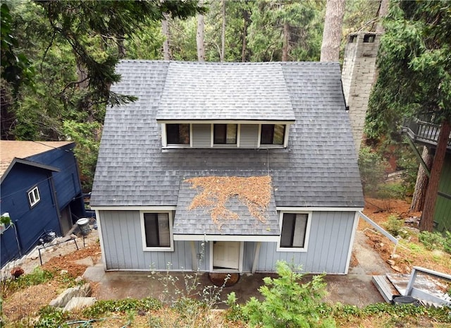 view of front facade featuring a shingled roof and a chimney