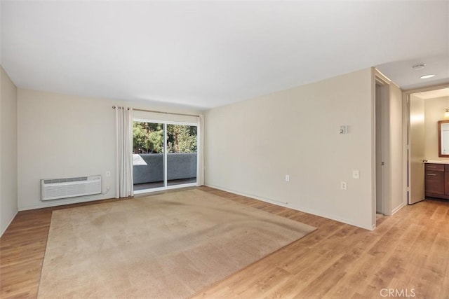 empty room featuring an AC wall unit and light wood-style flooring