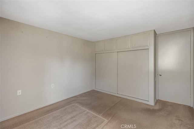 unfurnished bedroom with light carpet and a closet