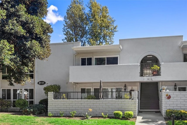 view of front of property featuring fence, a balcony, and stucco siding