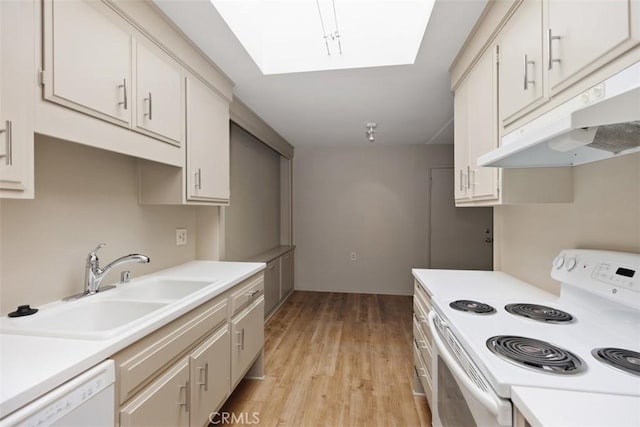 kitchen with a skylight, light countertops, a sink, white appliances, and under cabinet range hood