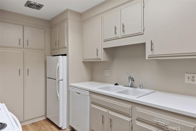 kitchen with white appliances, visible vents, light countertops, and a sink