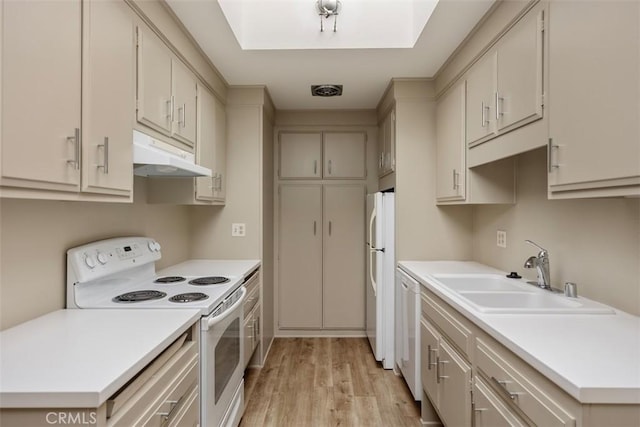 kitchen with white appliances, light countertops, light wood-type flooring, under cabinet range hood, and a sink