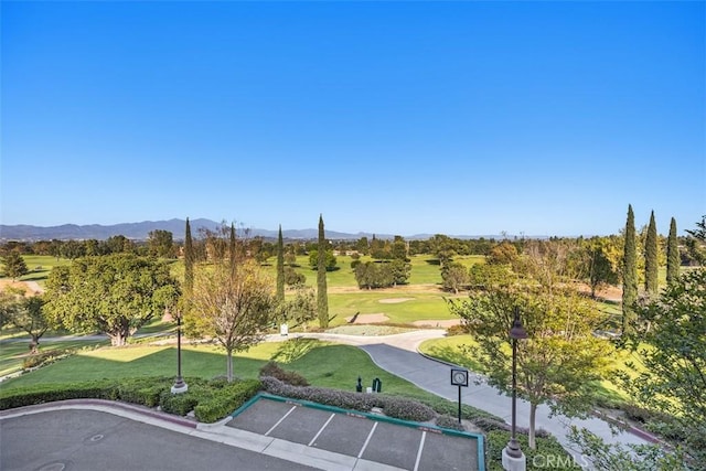 view of property's community with uncovered parking, a mountain view, and a lawn