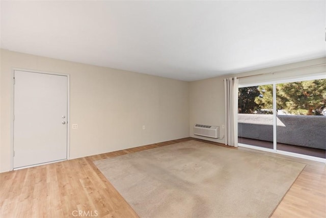 spare room featuring a wall unit AC and light wood-style flooring