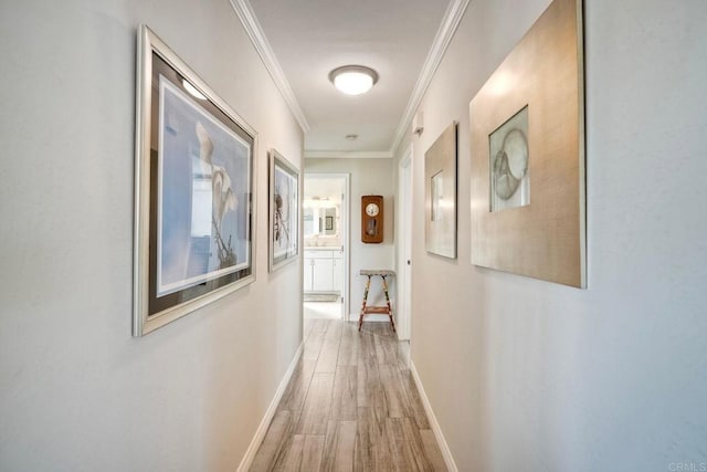 corridor with ornamental molding, wood finished floors, and baseboards