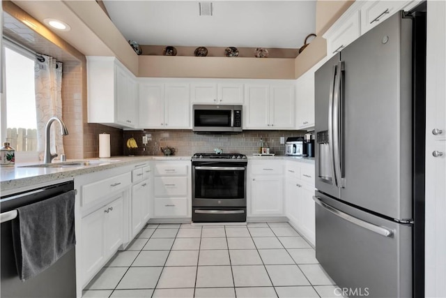 kitchen with stainless steel appliances, visible vents, backsplash, light tile patterned flooring, and a sink