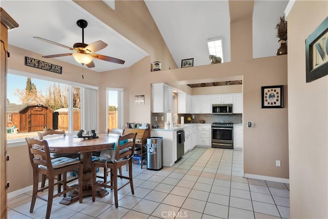 dining space featuring a ceiling fan, lofted ceiling, baseboards, and light tile patterned floors