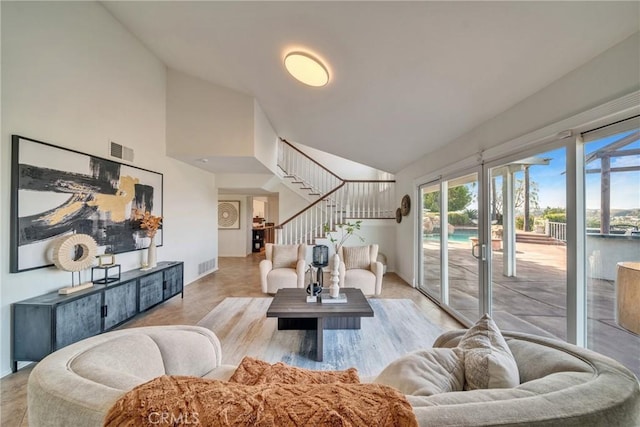 living area with stairs, high vaulted ceiling, and visible vents