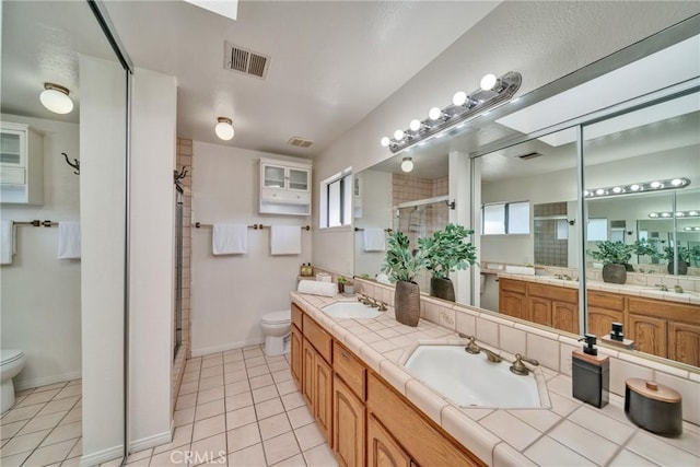 bathroom with a stall shower, visible vents, a sink, and toilet