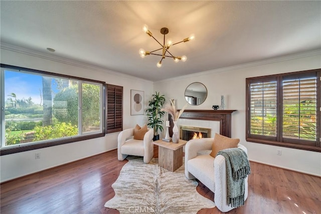 sitting room featuring ornamental molding, wood finished floors, a tile fireplace, and an inviting chandelier