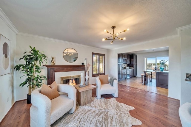 living area featuring a fireplace, a chandelier, wood finished floors, and ornamental molding