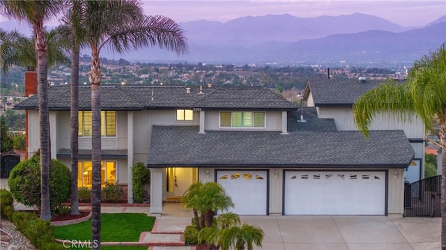 view of front of home with driveway, a shingled roof, a garage, and a mountain view