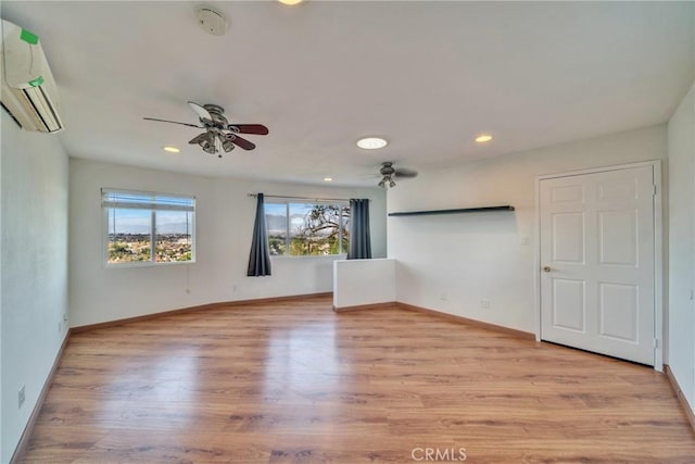 spare room featuring recessed lighting, baseboards, wood finished floors, and a wall mounted AC