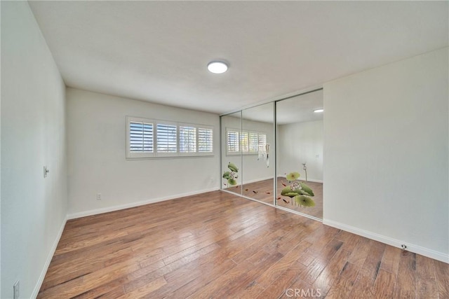 unfurnished room featuring baseboards and hardwood / wood-style flooring