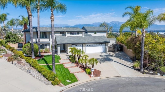 traditional home featuring fence, a mountain view, and concrete driveway