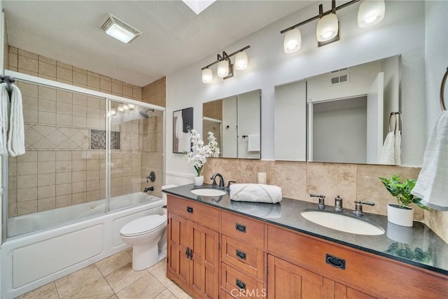 bathroom with bath / shower combo with glass door, decorative backsplash, a sink, and tile patterned floors