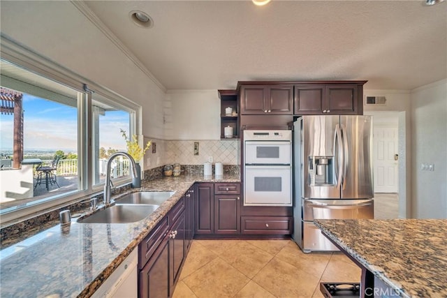 kitchen featuring crown molding, double oven, a sink, dark stone counters, and stainless steel fridge with ice dispenser