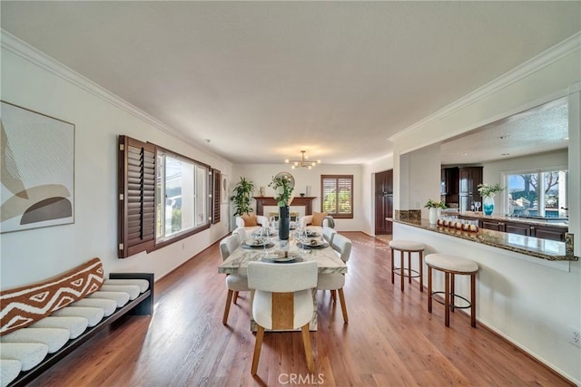 dining room with a chandelier, ornamental molding, wood finished floors, and baseboards