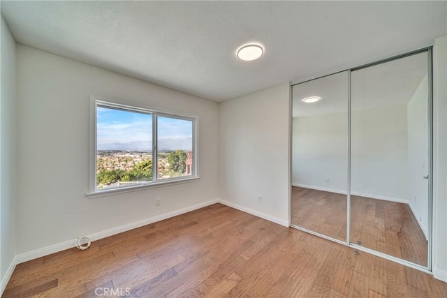 unfurnished bedroom with a closet, baseboards, and wood finished floors