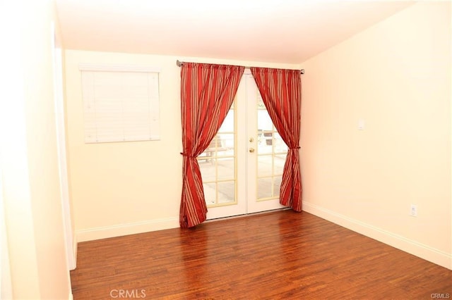 spare room with baseboards and wood finished floors