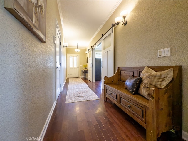 interior space featuring a barn door, dark wood-type flooring, crown molding, and a textured wall