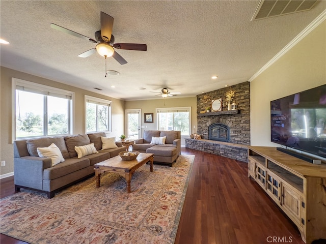 living room with visible vents, ornamental molding, a stone fireplace, a textured ceiling, and wood finished floors