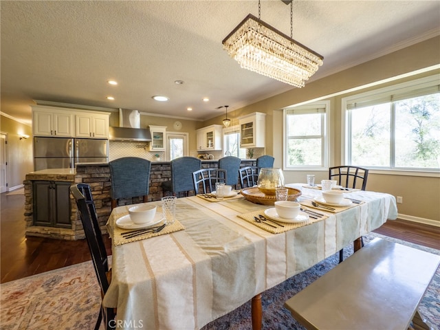 dining space featuring dark wood-type flooring, crown molding, a textured ceiling, and baseboards