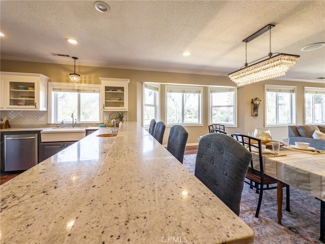 kitchen with light stone counters, dishwasher, backsplash, and a sink