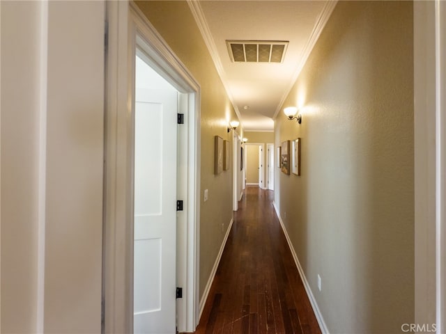 corridor with baseboards, dark wood-type flooring, visible vents, and crown molding