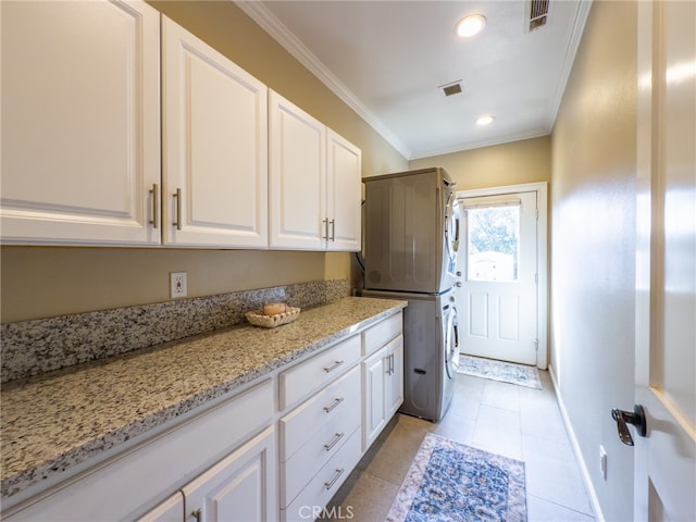 laundry area with cabinet space, crown molding, visible vents, and stacked washer / drying machine