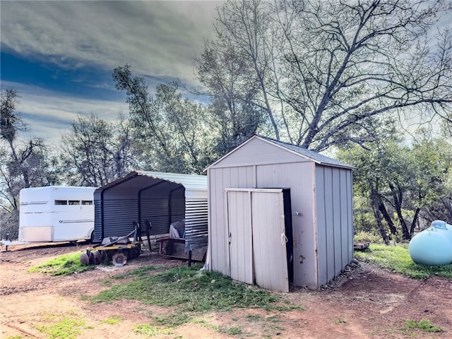 view of shed featuring a carport and driveway