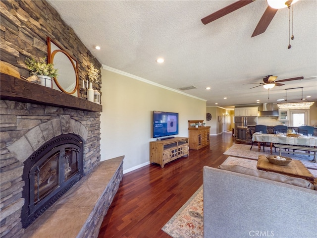 living area featuring ornamental molding, a stone fireplace, a textured ceiling, and wood finished floors