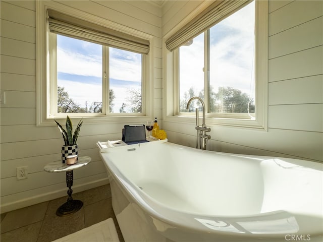 full bathroom featuring tile patterned flooring, a freestanding tub, and wooden walls