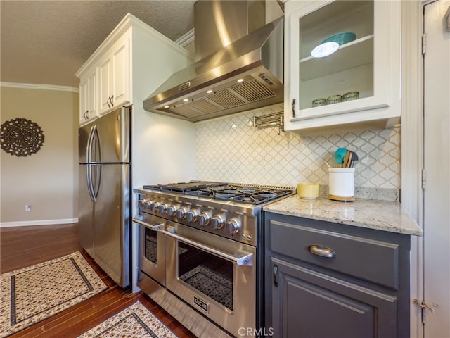 kitchen featuring dark wood-style floors, light stone counters, appliances with stainless steel finishes, white cabinets, and exhaust hood