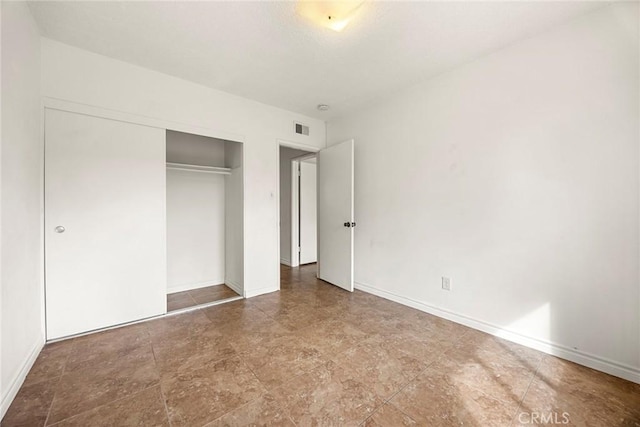 unfurnished bedroom with a closet, visible vents, and baseboards