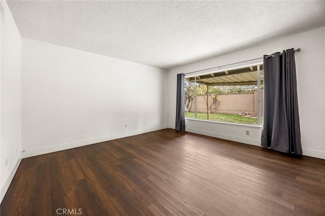 unfurnished room featuring a textured ceiling, baseboards, and wood finished floors