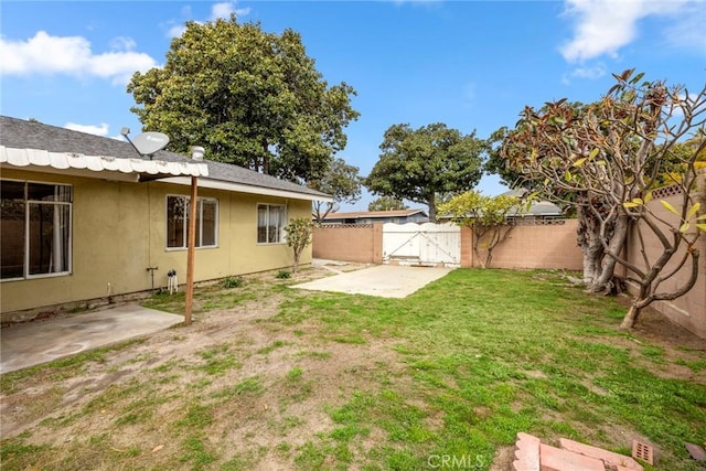 view of yard with a patio area, a fenced backyard, and a gate