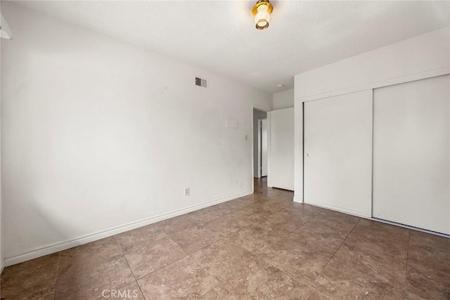 unfurnished bedroom with a closet, visible vents, and baseboards