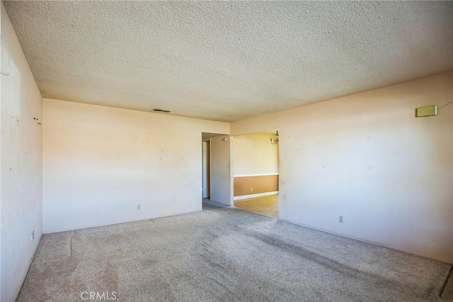 carpeted empty room featuring visible vents and a textured ceiling