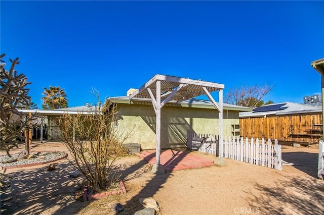 view of front facade featuring a patio area, fence, and stucco siding