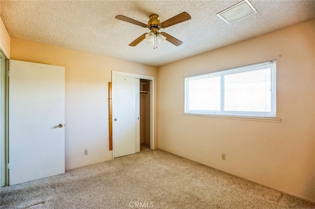 unfurnished bedroom with carpet, a closet, visible vents, a ceiling fan, and a textured ceiling