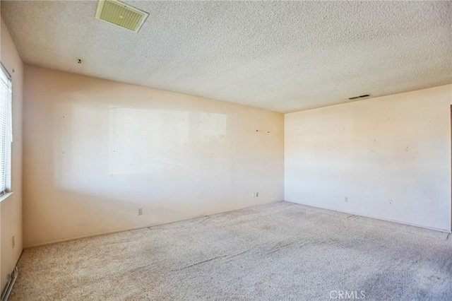 carpeted spare room featuring visible vents and a textured ceiling