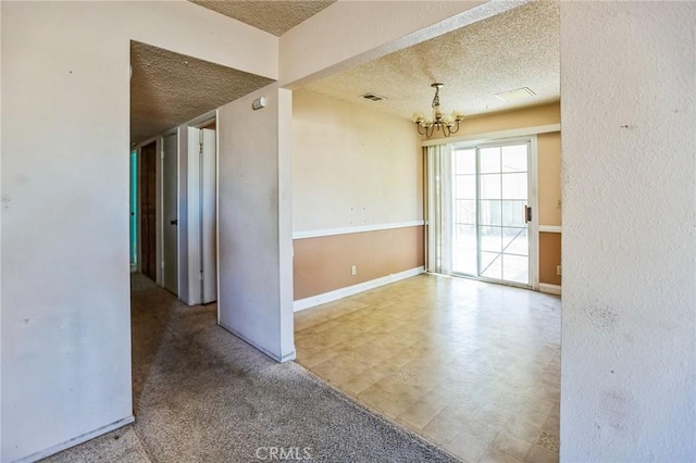 empty room with baseboards, visible vents, a chandelier, and a textured ceiling