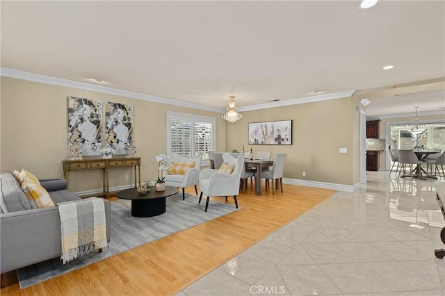 living room featuring light tile patterned floors, ornamental molding, and an inviting chandelier