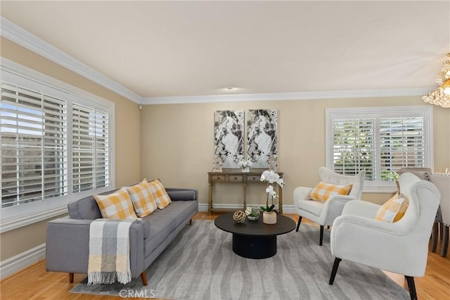 living room featuring an inviting chandelier, crown molding, baseboards, and wood finished floors