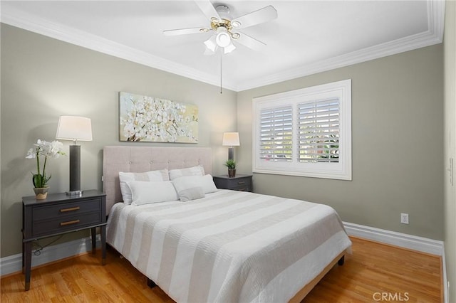 bedroom featuring a ceiling fan, crown molding, baseboards, and wood finished floors