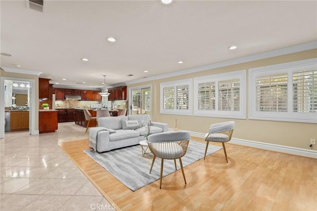 living room with baseboards, visible vents, and crown molding