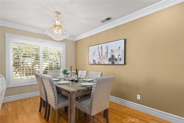 dining space with baseboards, an inviting chandelier, wood finished floors, and crown molding