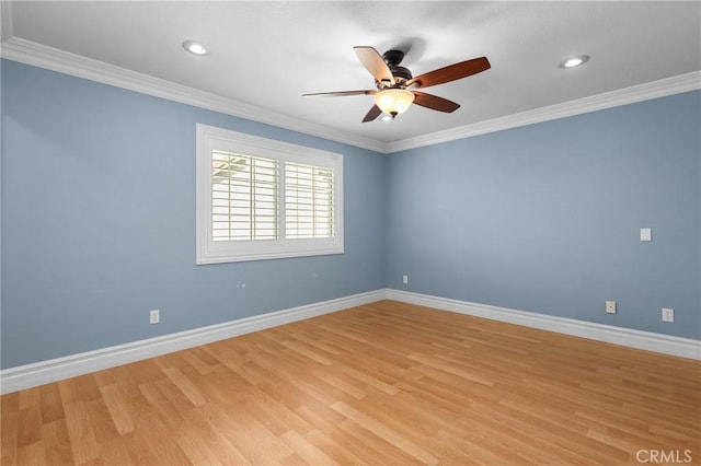 spare room featuring light wood-style floors, crown molding, and baseboards